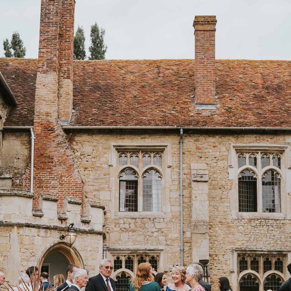 Wedding guests talking and drinking champagne outside Notley Abbey wedding venue