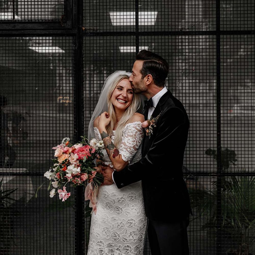 Bride in boho two piece lace bridal outfit with large mixed colourful bouquet and groom in dark tux with bowtie