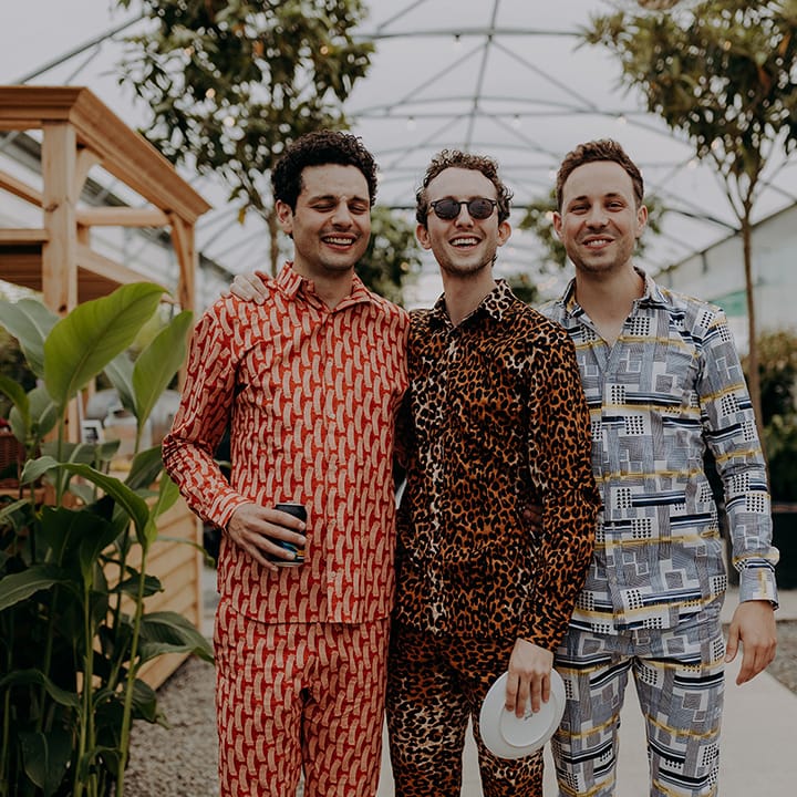 Three guests wearing bright and patterned shirts and trousers