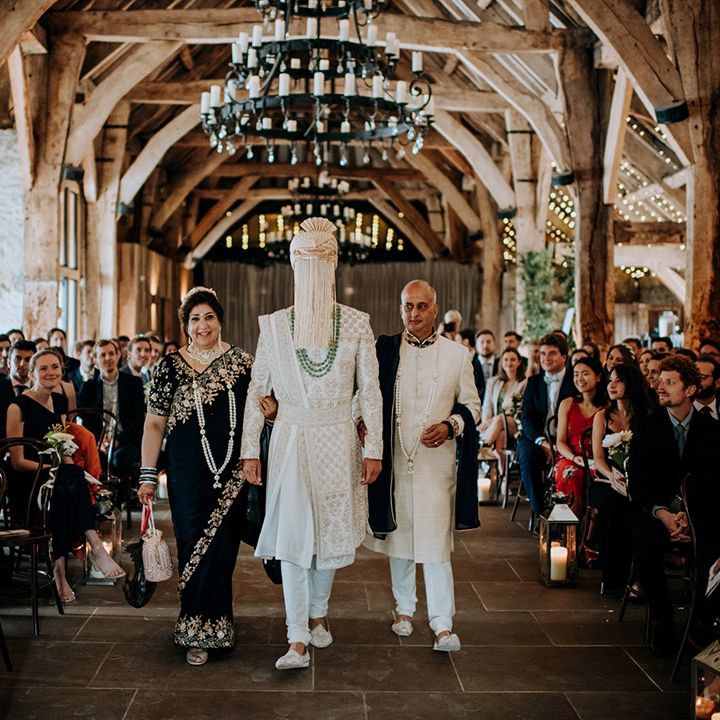 Groom walks through the Tithe Barn Bolton Abbey surrounded by guests