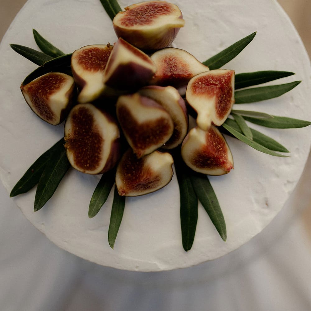 Simple white iced ewedding cake with fig and olive leaf decor