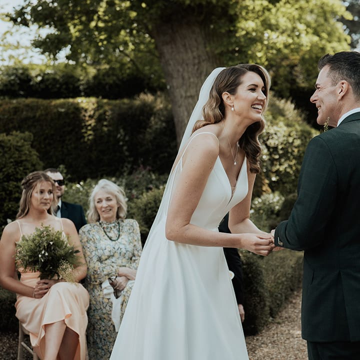 The bride and groom at their outdoor Kelmarsh Hall and Garden wedding surrounded by their guests 