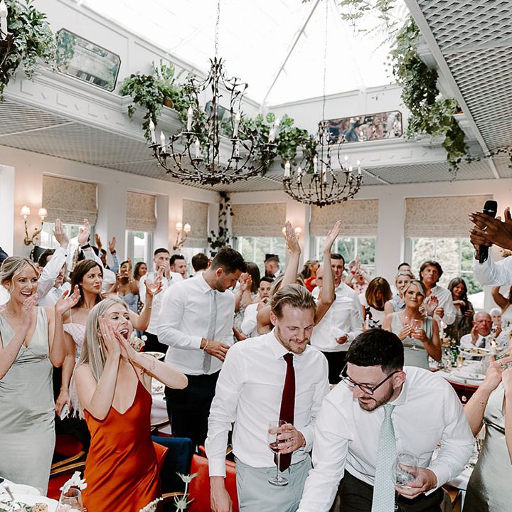 Wedding guests at the wedding breakfast celebrating the wedding by singing and dancing 