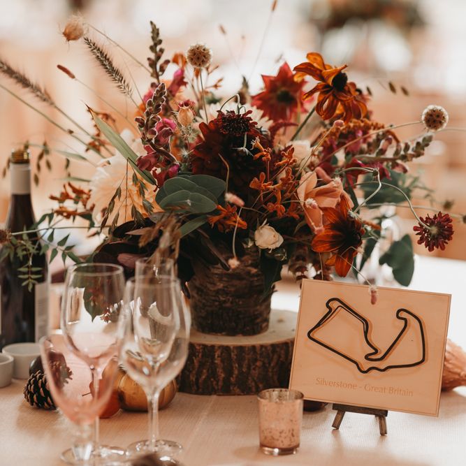 Rustic centrepiece with wooden tree slice and grand prix track table names and signs 