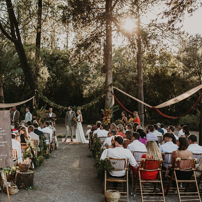Outdoor forest wedding ceremony with wooden wedding sign 