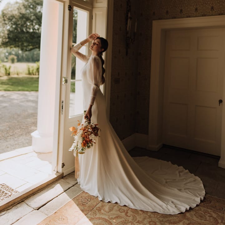 Bride holding autumnal bouquet at Reymerston Hall