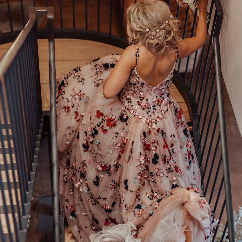 Bride walks up the stairs and wears blonde hair in low up do with pearl hair accessories 