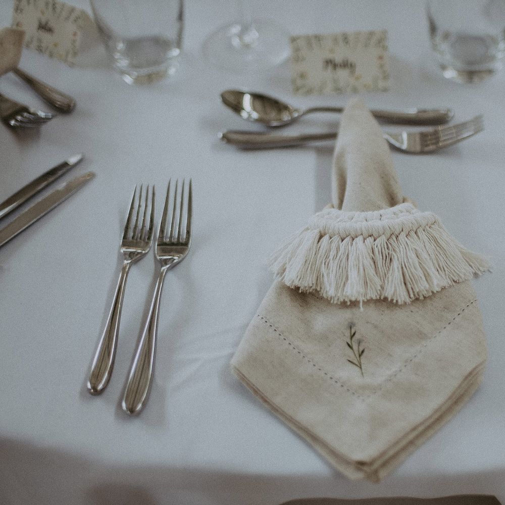 White wedding breakfast table with silverware, glassware and leaf embroidered napkins with macrame napkin tie for Isle of Wight wedding with macrame wedding decor
