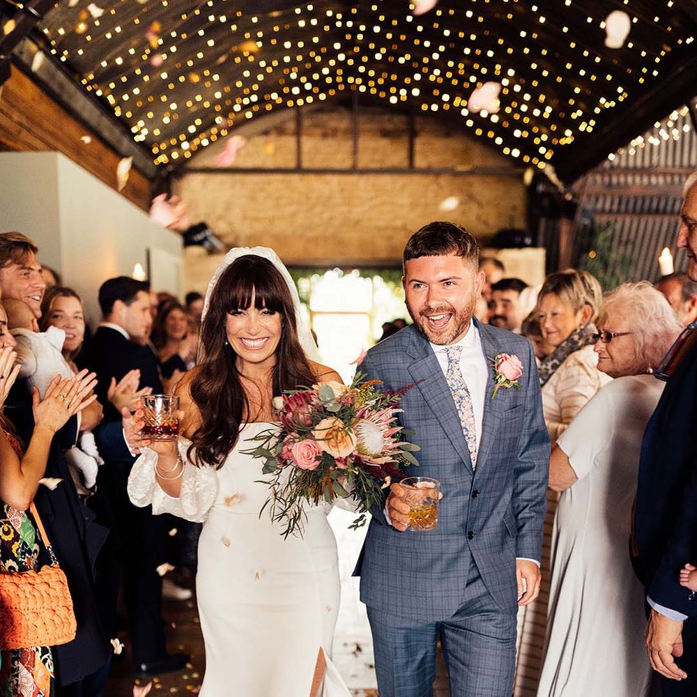 Bride & groom walk down the aisle as bride wears Rime Arodaky dress with puffed sleeves and gold Miu Miu platform sandals 