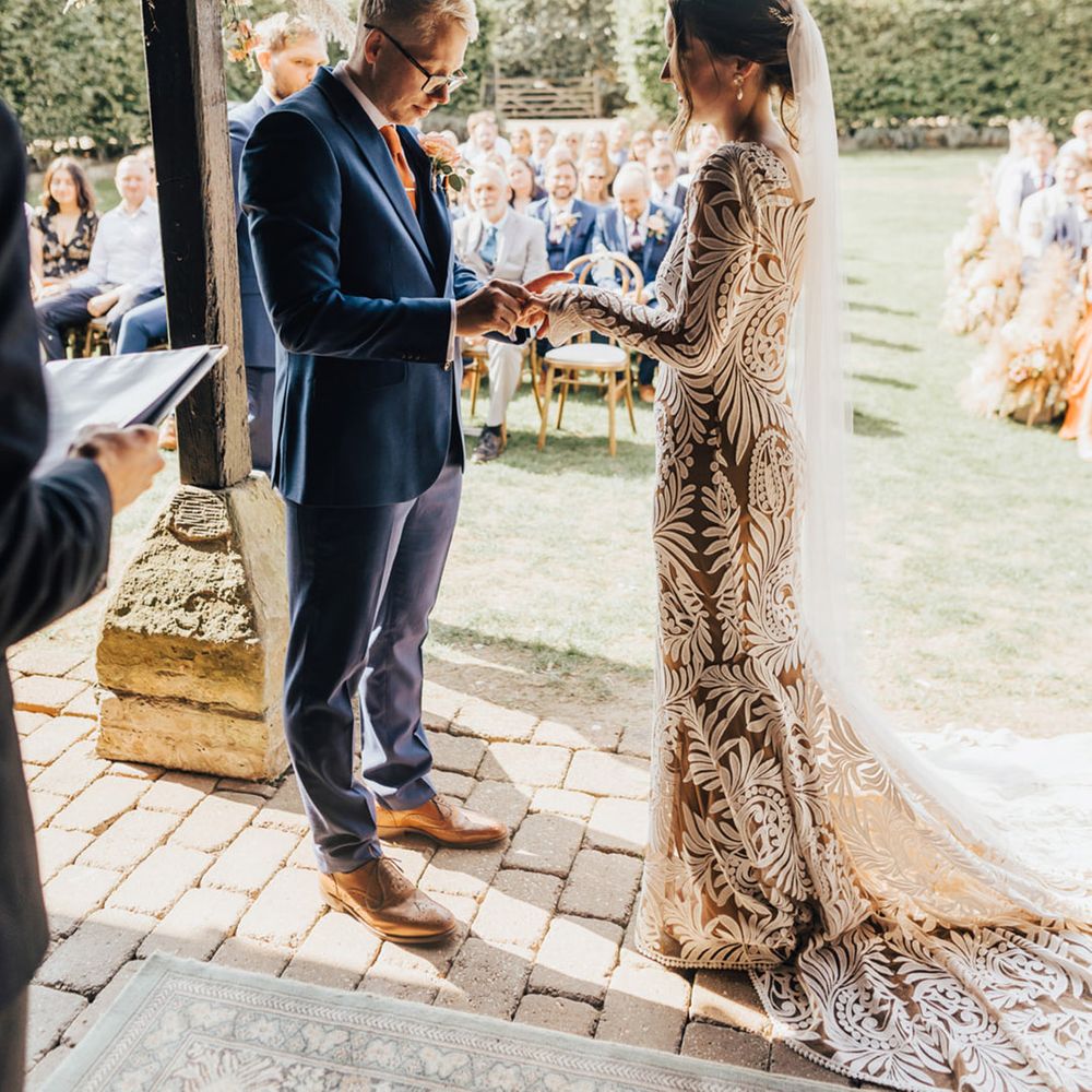 Barn wedding Groom in Navy fitted suit with burnt orange tie & bride in lace boho dress 