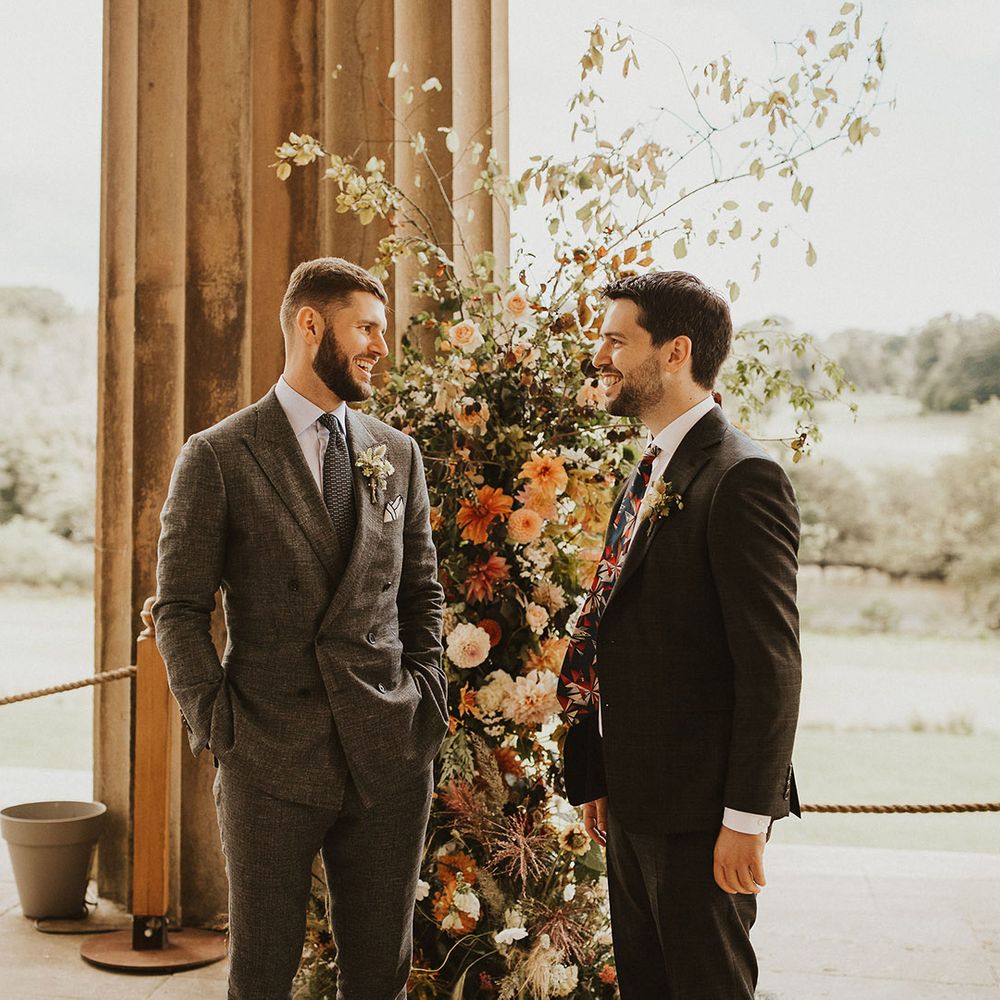 Groom stands with his groomsmen on wedding day as they talk before wedding ceremony