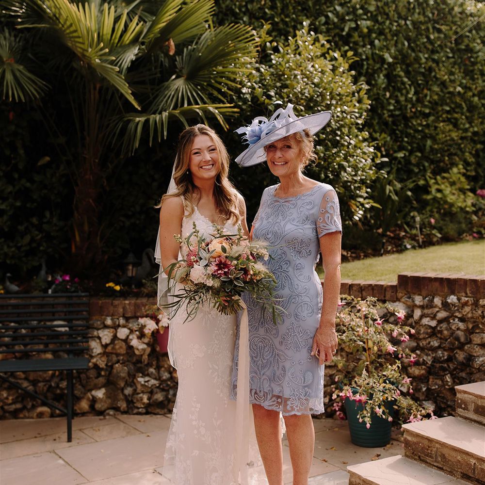 Bride with mother of the bride in blue lace dress and matching hat