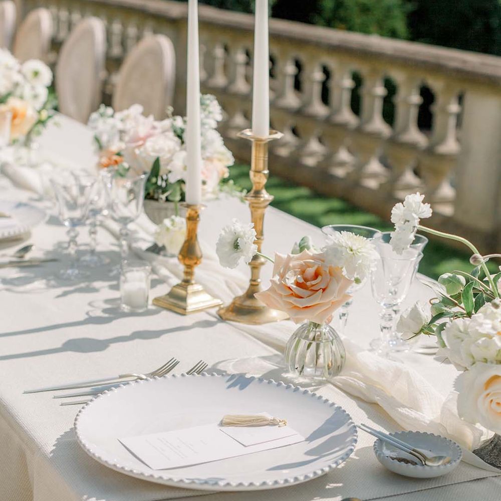 Simple tablescape complete with white plates and pastel floral bouquets 
