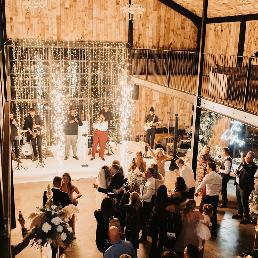 Fairy lights backdrop for winter wedding with live band entertainment and neon sign and chandeliers