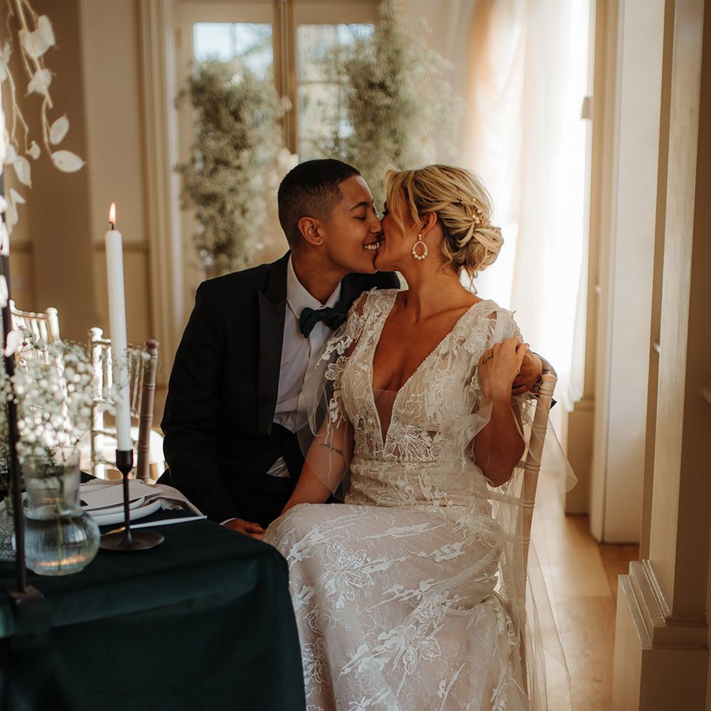 LGBTQI+ couple kissing at Hodsock Priory wedding reception with the bride in a lace wedding dress 