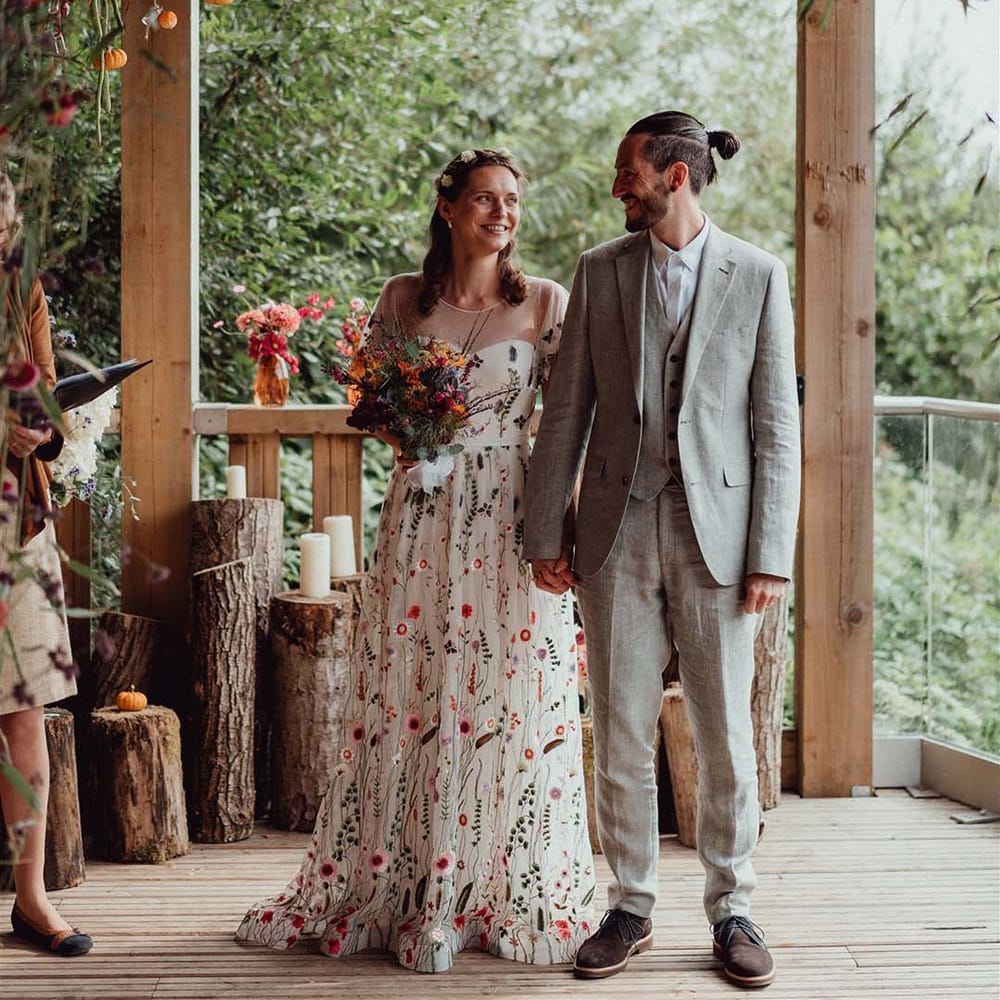 Bride and groom at the altar for their outdoor wedding with tree trunk candle holders and hanging plant decor
