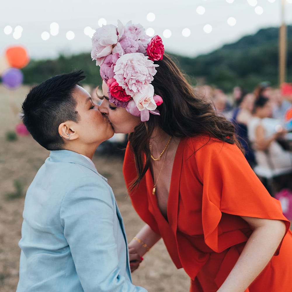 Couple kisses on their wedding day with pink floral crown at LGBTQI+ wedding