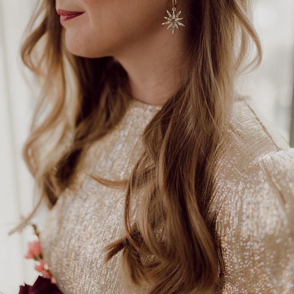 Bride with pearl hair clip accessory and star earrings with gold eye makeup and gold wedding dress