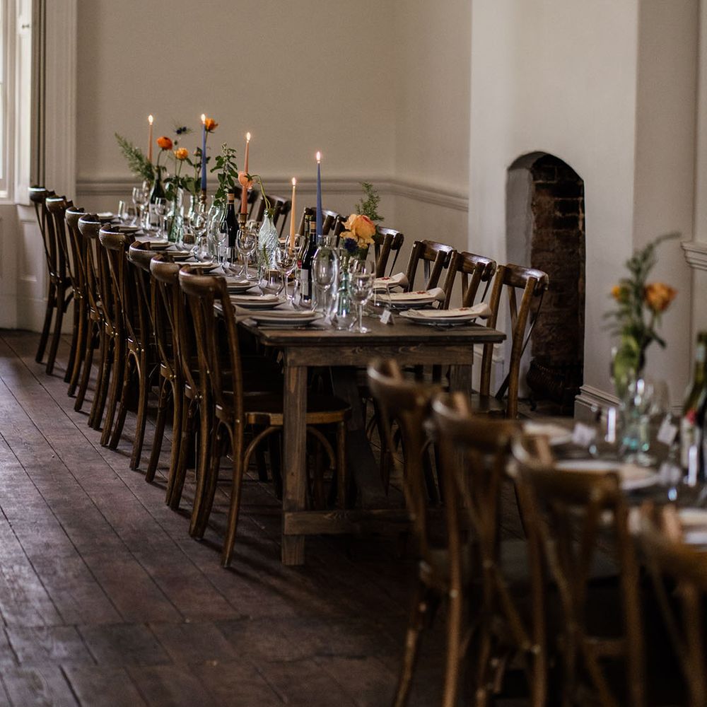 Wooden banquet table with pink, blue, and yellow candles and lots of foliage 