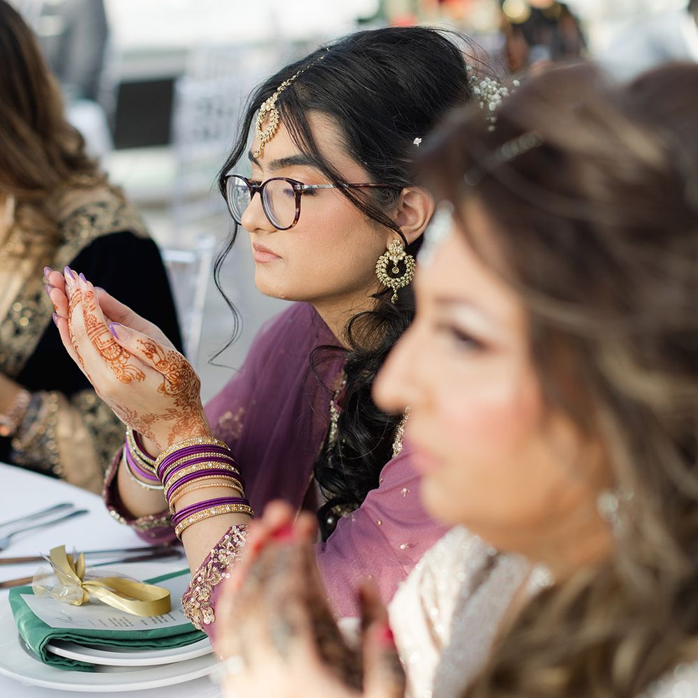 Wedding guests cup hands together at table during reception 