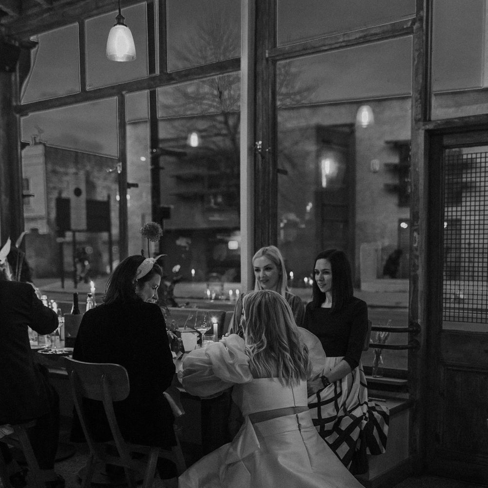 Bride in JESUS PEIRO bridal separates leaning down talking to her guests at her reception 