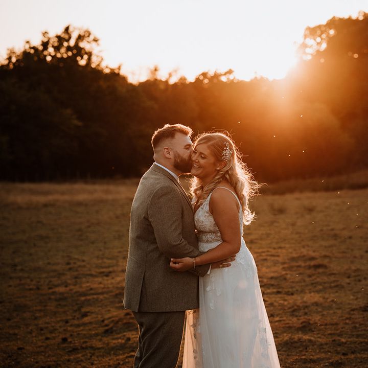 Groom kisses the bride on the cheek during their golden hour portraits 