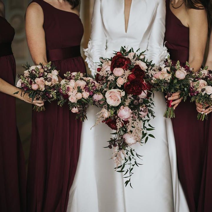 Bride holding a cascading peony and rose pink and red wedding bouquet with bridesmaids holding smaller versions