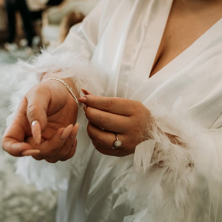 Bride with long neutral wedding nails putting on her diamond tennis bracelet for the wedding 