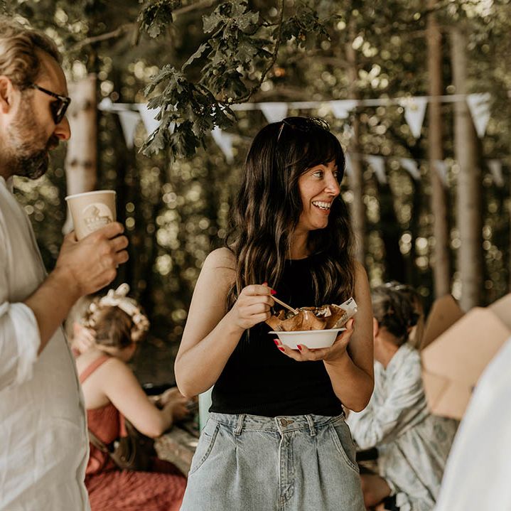 A wedding guest holds a recyclable cardboard box eating Mexican food served from food trucks 