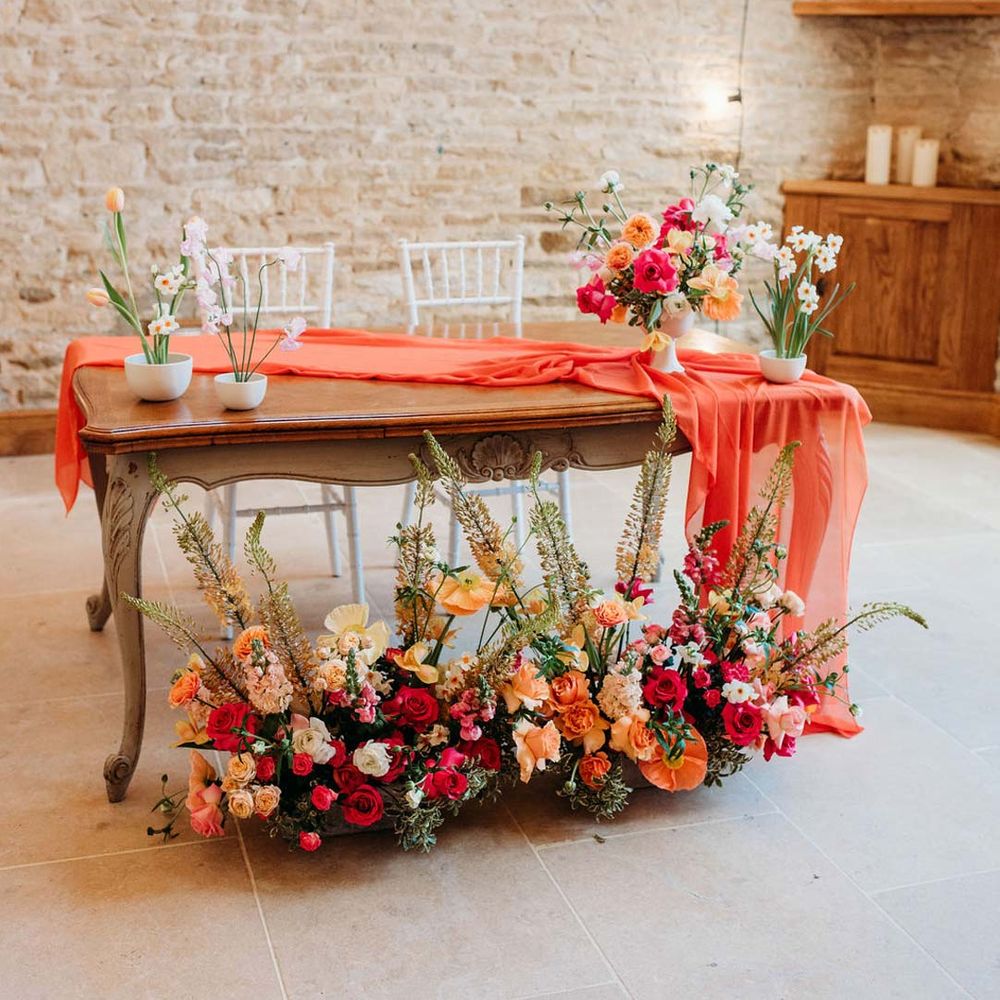 Merriscourt wedding venue reception room with wooden table with orange table runner and mixed seasonal flower arrangements 