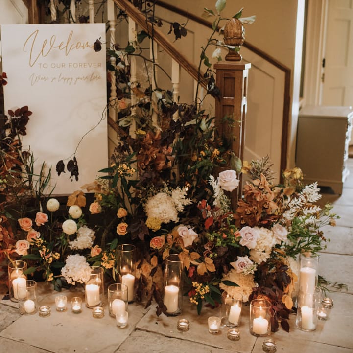 Welcome wedding sign with flower display and candles at Reymerston Hall