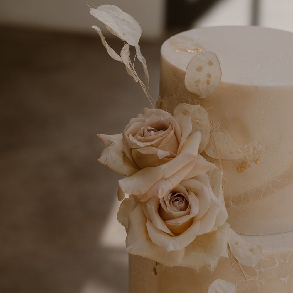 Two tiered off white marble effect wedding cake with rose decoration and gold leaf detailing by Bohemian Bakehouse