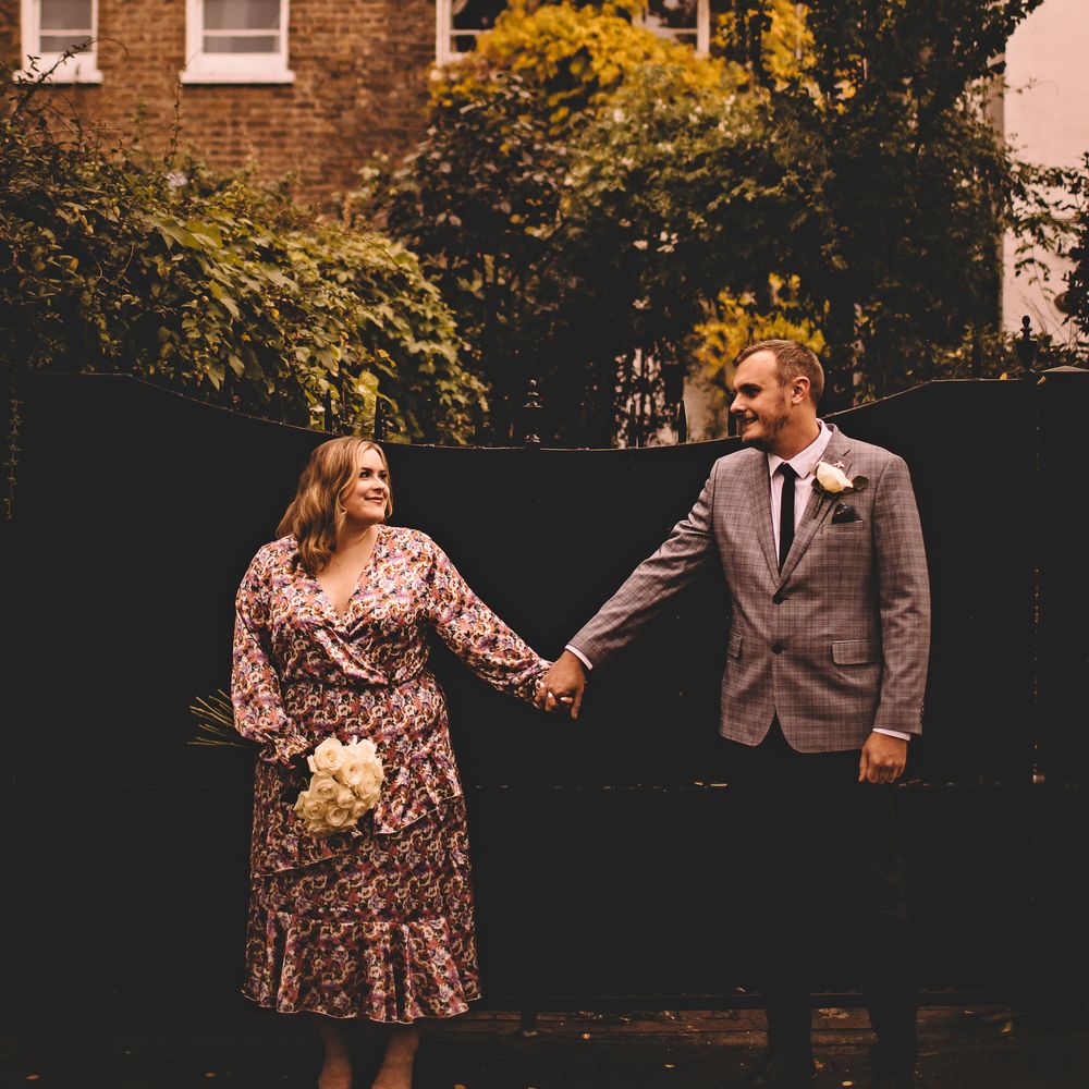 Bride & groom hold hands as they wear casual wedding outfits on the day of their wedding