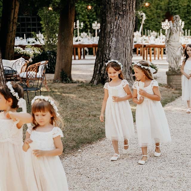 Flowers girls walk down the aisle wearing white dresses and white floral crowns | Royal Studio