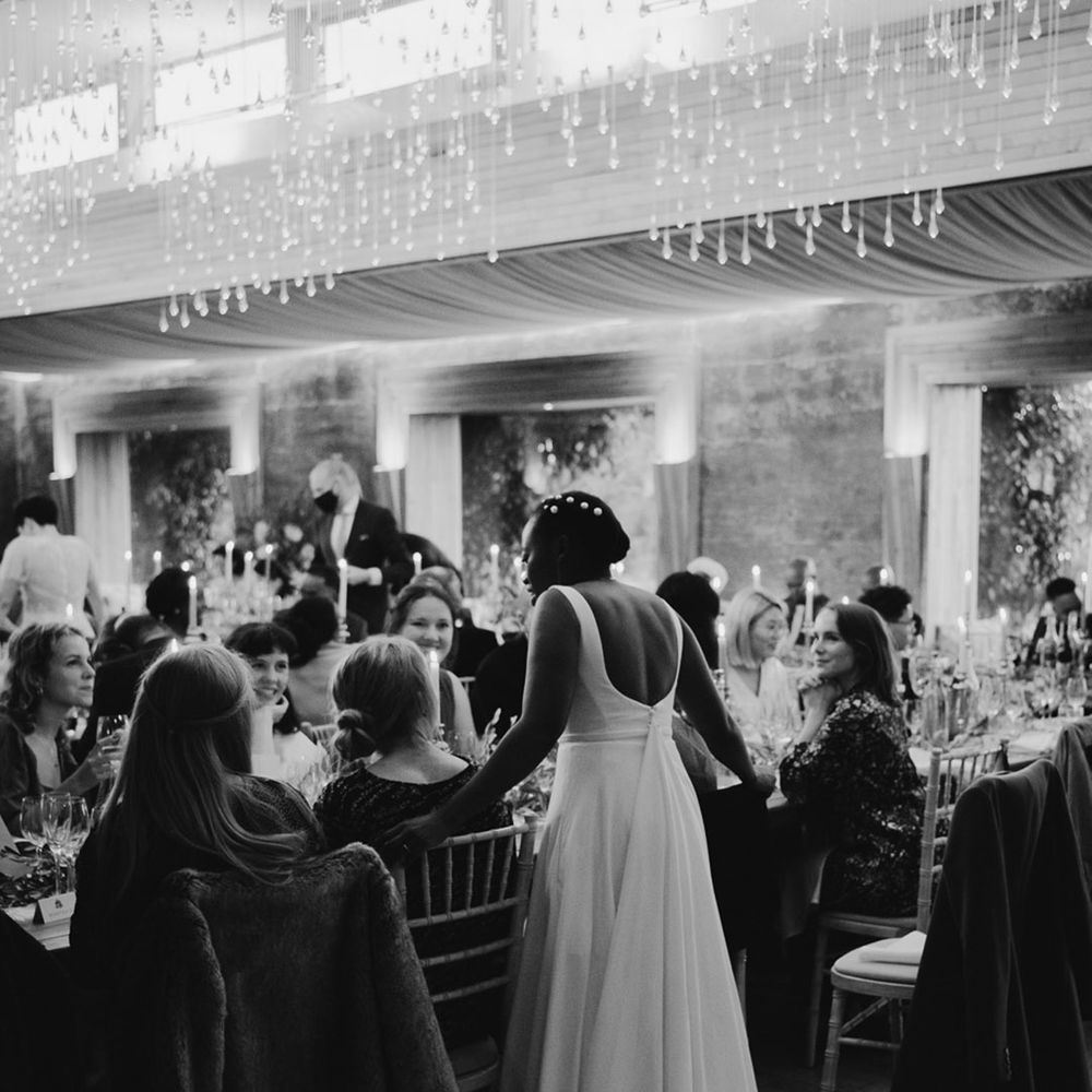 Black bride with peal hair pins talking to her guests during the wedding reception 