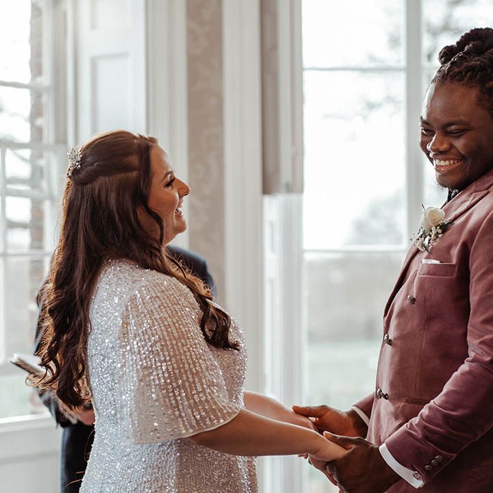 Bride & groom hold hands and look lovingly at one another on their wedding day