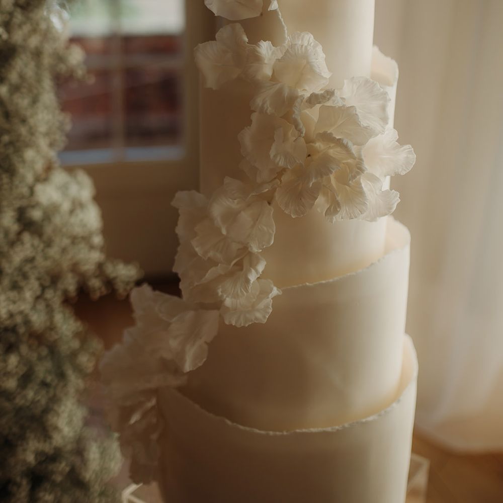 white cascading flower detail on white wedding cake 