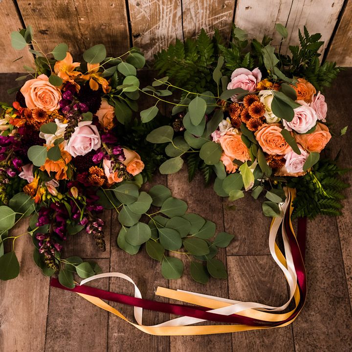 Different wedding bouquets with pink, purple, orange flowers including roses and fern leaves with one tied with multi coloured ribbons