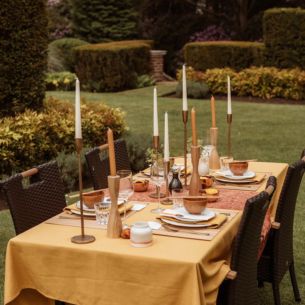 Japanese wedding at Gorse Hill with outdoor wedding table scape with a yellow table cloth, wood and copper candlestick holders, taper candles, rice bowls and chopsticks 