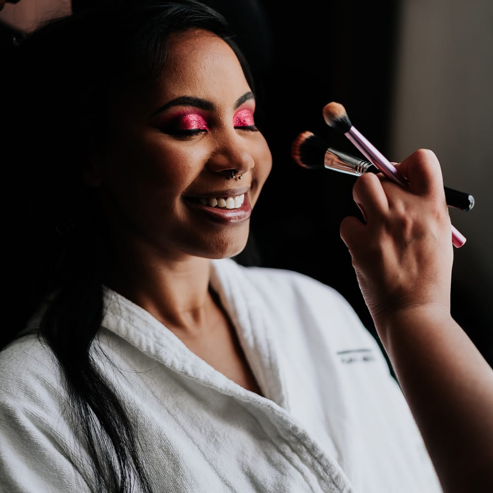 Bride wears bold pink glitter eyeshadow on the day of her wedding with red lip 