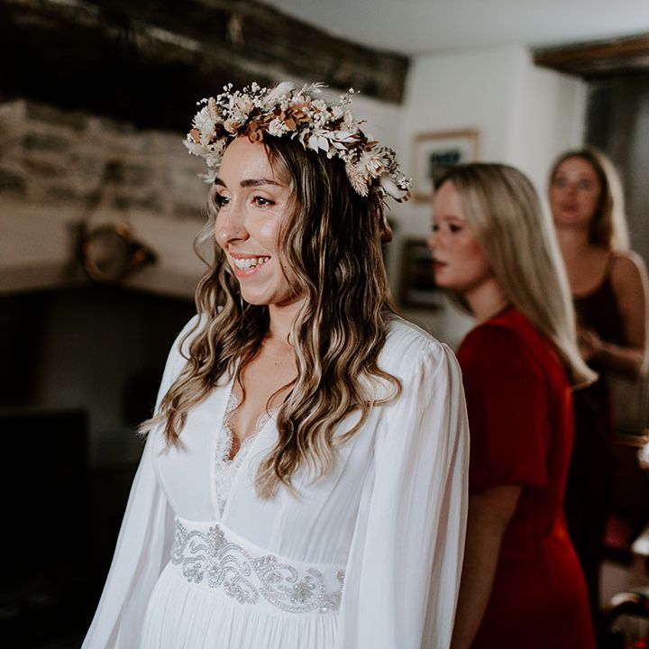 Bride wears floral crown tied with pale pink ribbon and wears her hair in loose curls