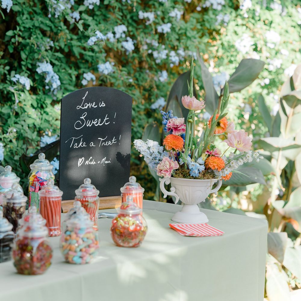 Colourful sweet station complete with chalkboard and colourful floral arrangement 