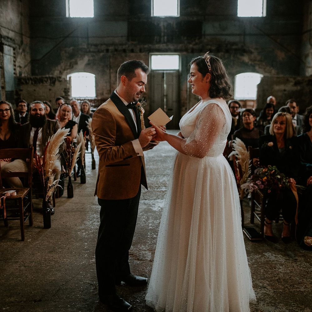 Bride and Groom exchange rings at alter in front of pampas grass lined aisle