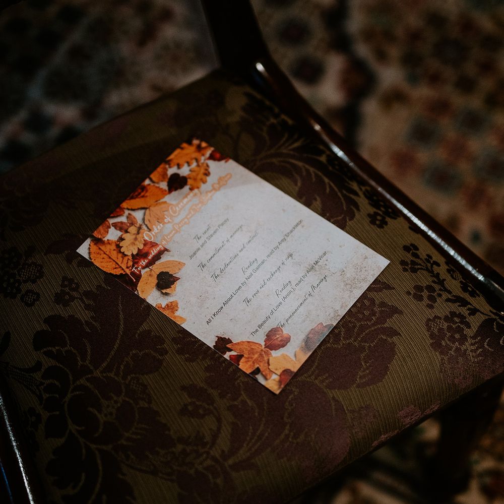 Autumnal themed wedding order of ceremony stationery with orange, yellow and brown leaf decorations