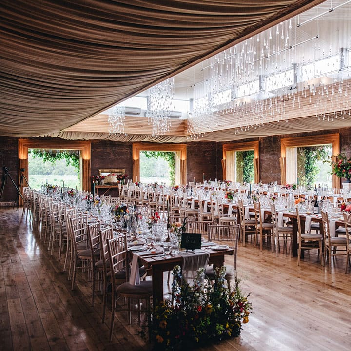 Elmore Court wedding venue with long banquet tables covered with white table runners and subtle pops of green from the wedding stationery and favours 