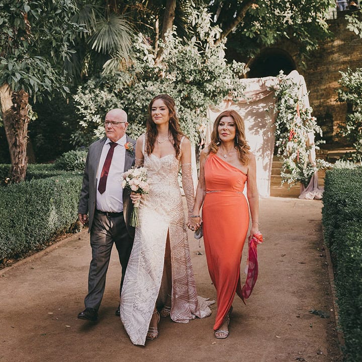 mother and father of the bride walking their daughter down the aisle in a sparkly wedding dress