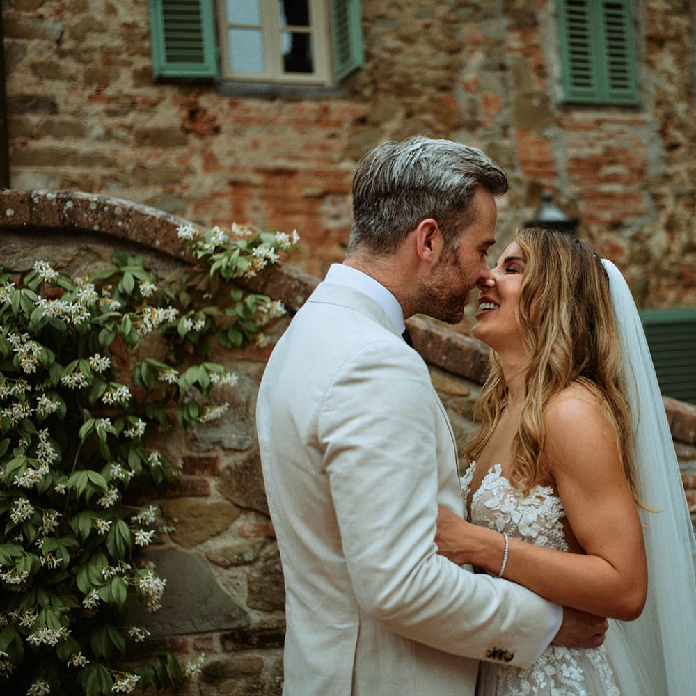 Bride and groom share a kiss in front of italian villa at destination wedding in Tuscany