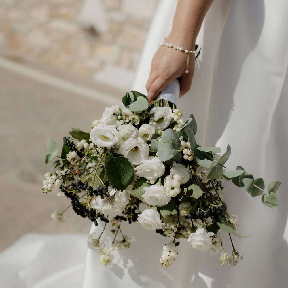 Bridal bouquet featuring white berries, italian ranunculus and eucalyptus at Greek destination wedding