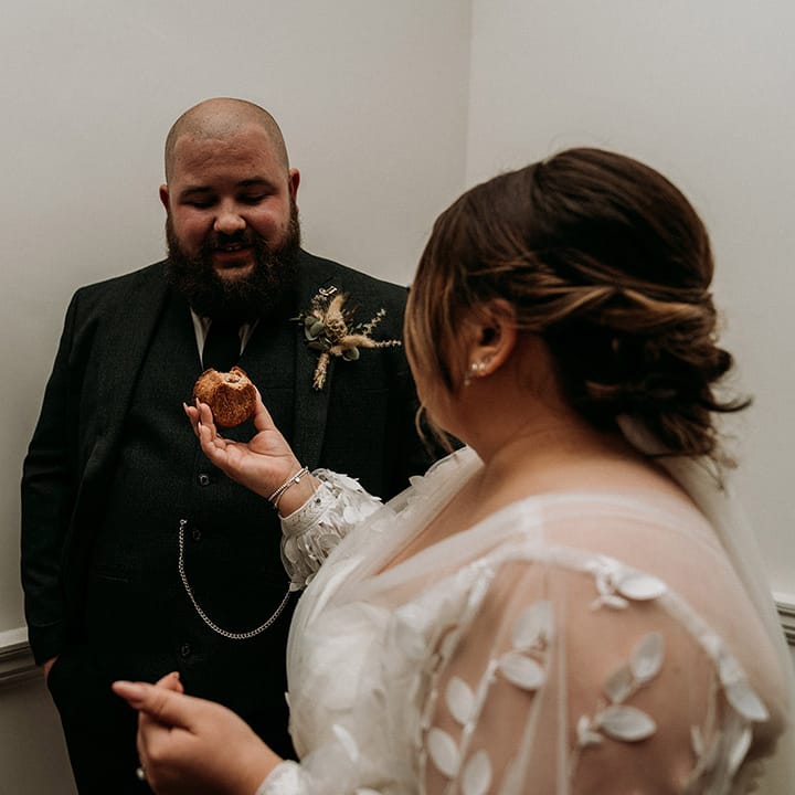 The bride feeds the groom a pork pie as they cut their cheese tower 