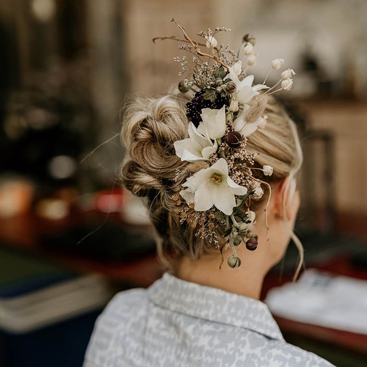 Bride with blonde hair in a slick updo wearing a white flower hair accessory 